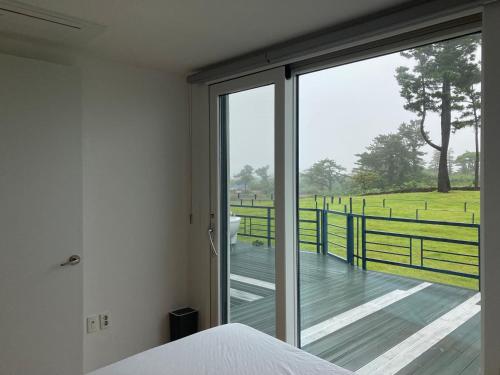 a bedroom with a view of a wooden deck at Bibidoongdoong in Jeju