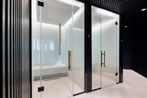 une porte pivotante en verre dans une chambre avec lavabo dans l'établissement INVENTIST Hotel Sports Academy Istanbul, à Istanbul