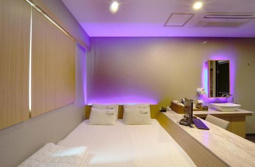 a room with a bed and a sink and purple lighting at Nampo Comma Hotel in Busan