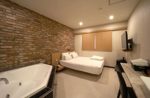 a bathroom with a bed and a bath tub at Nampo Comma Hotel in Busan