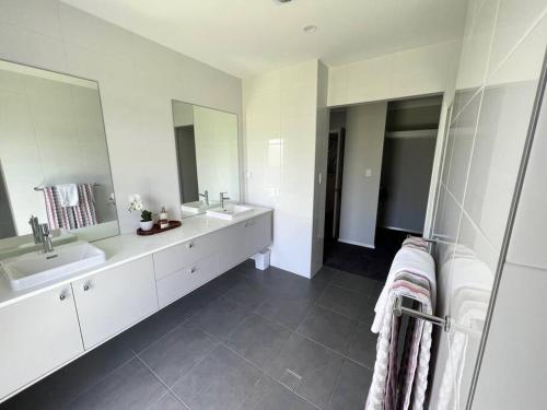 a white bathroom with two sinks and two mirrors at 'Kaia' relaxing Manyana Beach getaway in Manyana
