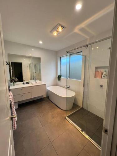 a bathroom with a tub and a sink and a shower at 'Kaia' relaxing Manyana Beach getaway in Manyana