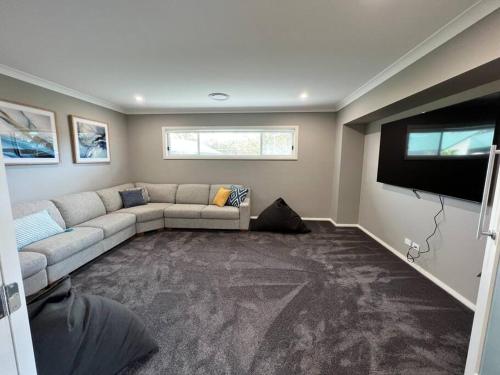 a living room with a couch and a flat screen tv at 'Kaia' relaxing Manyana Beach getaway in Manyana
