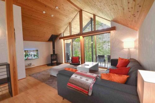 a living room with a gray couch and a large window at Muskoka House — Stunning architect-designed chalet in Hakuba