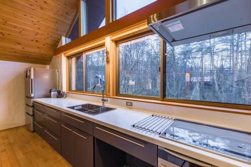 a kitchen with a sink and two windows at Muskoka House — Stunning architect-designed chalet in Hakuba