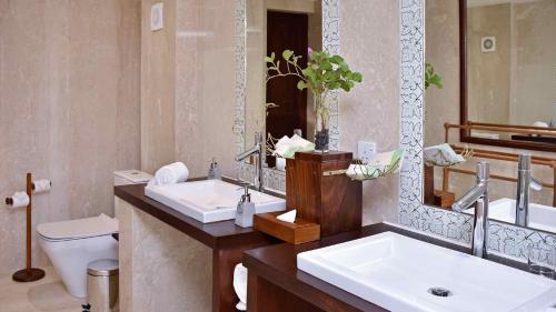 a bathroom with two sinks and a toilet and a mirror at Wattura Resort & Spa in Negombo