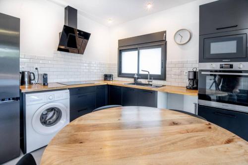 a kitchen with a wooden table and a washing machine at Villa standing 52 in Ravine des Cabris