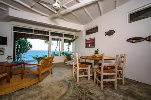 a dining room with a table and chairs and the ocean at The Overhang in Dar es Salaam
