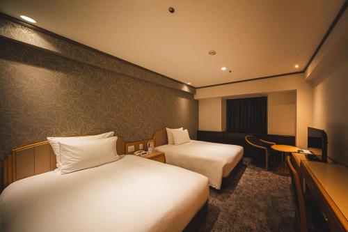 a hotel room with two beds and a television at ANA Crowne Plaza Matsuyama by IHG in Matsuyama