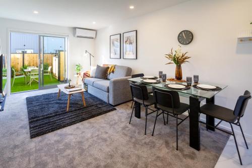 een woonkamer met een tafel en stoelen en een bank bij The happy hideaway 2 bed 2 bath in Christchurch