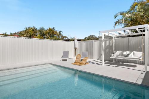 una piscina con 2 sedie a sdraio e un patio con piscina di Paradise Palms Mooloolaba - Beach House a Mooloolaba