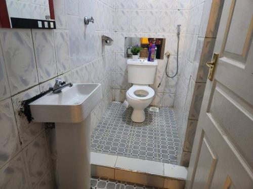 Łazienka z białą toaletą i umywalką w obiekcie Wusiiza Homestay Kisumu w mieście Kisumu