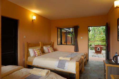 two beds in a room with orange walls at Depche Village Resort in Bandipur