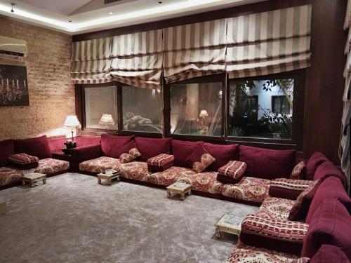 a living room with a red couch with pillows at استراحة ريف طيبة in Al Madinah