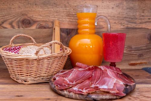 a table with a basket of bread and a bottle of orange juice at B&B El Lares - B&B L'Avez in Canale dʼAgordo