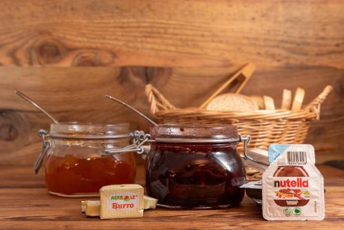 a table with two jars of honey and a basket of bread at B&B El Lares - B&B L'Avez in Canale dʼAgordo