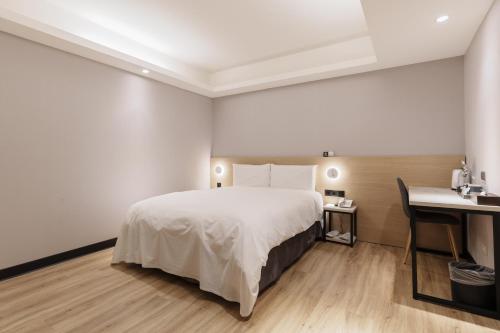 Habitación de hotel con cama y escritorio en Hubhotel Benqiao Inn Far Eastern Branch en Taipéi