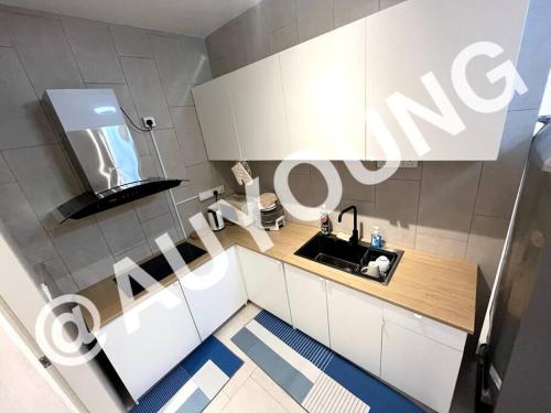 eine Küche mit weißen Schränken, einem Waschbecken und einem Spiegel in der Unterkunft Geo Bukit Rimau Apartment in Shah Alam