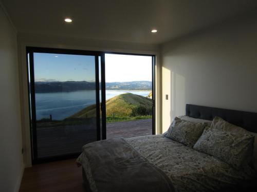 a bedroom with a bed and a large sliding glass door at Ocean Waters in Mahia