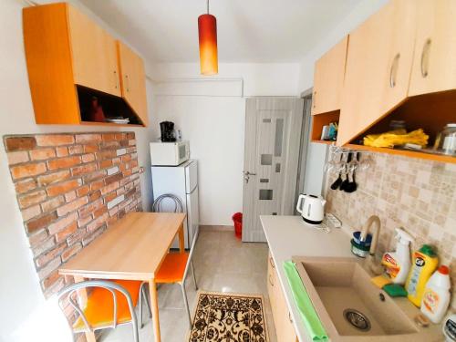 małą kuchnię ze zlewem i ścianą z cegły w obiekcie Apartment Eminescu - A pleasant stay in Bacau w mieście Bacău