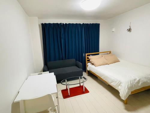 a bedroom with a bed and a chair and a table at STUDIO YONEGAHAMA l 米が浜通 in Yokosuka