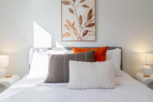 een wit bed met oranje en grijze kussens bij The happy hideaway 2 bed 2 bath in Christchurch