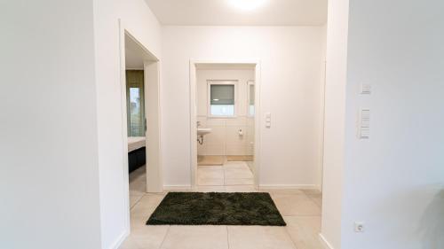een badkamer met witte muren en een zwart tapijt bij Apartments by KEN in Ramstein-Miesenbach