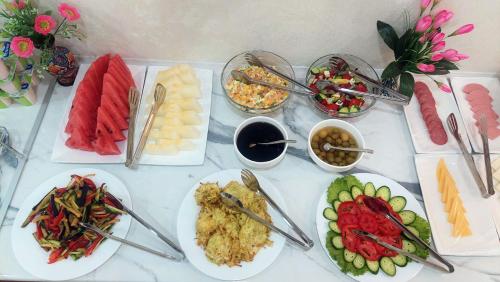 una mesa con platos de comida y cuencos de diferentes alimentos en Jahongir Premium en Samarcanda