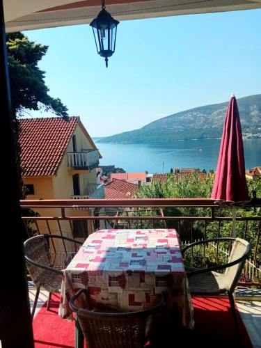 a table and chairs on a balcony with a view of the water at Guest House Cinderella in Herceg-Novi