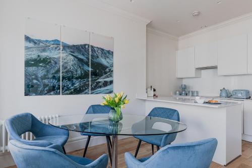 a dining room with a glass table and blue chairs at OFF Covent Garden SUPERB SPACIOUS BRIGHT LUXXE DESIGN HOME- YOUR WISH GRANTED! in London