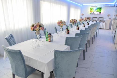 a row of tables and chairs in a room with flowers at La Luna Rustic Deluxe Apartment with Free Jacuzzi, Bikes & Covered Parking in Našice