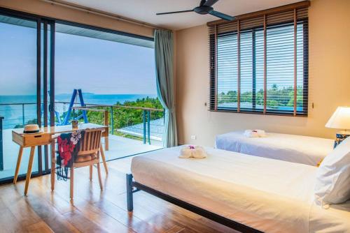 a bedroom with two beds and a desk and a balcony at 3 Bedrooms sea view villa in Haad Yao