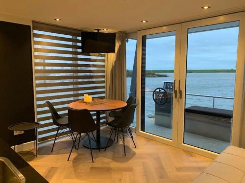 uma sala de estar com uma mesa e cadeiras e uma varanda em Tiny Houseboat Luxery em Zeewolde
