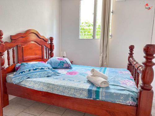 a bedroom with a wooden bed with towels on it at Chez Zèlou in Sainte-Anne