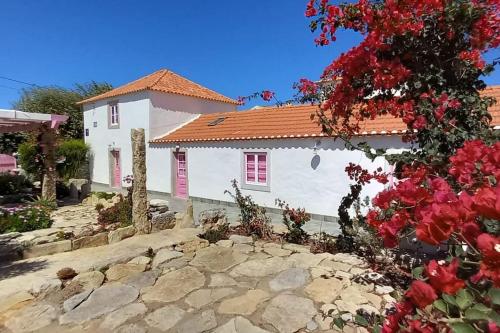 a white house with a red roof and some flowers at Casa das bonecas in Pernigem