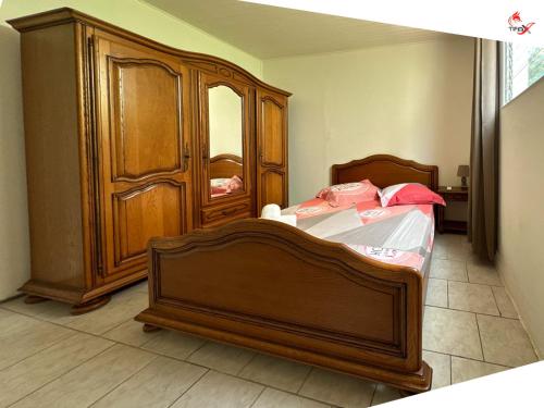 a bedroom with a wooden bed and a wooden cabinet at Chez Zèlou in Sainte-Anne