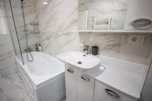 a white bathroom with a sink and a shower at DownTown Apartments in Rădăuţi