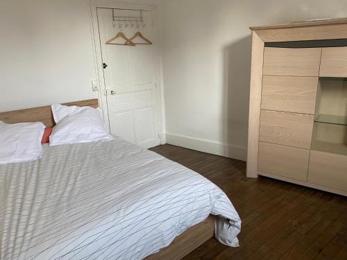 a bedroom with a white bed and a dresser at Appart Rez de jardin in Dijon