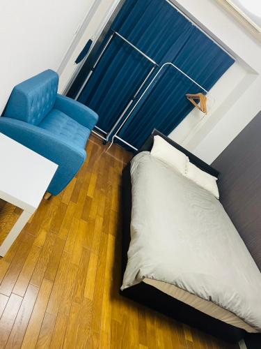 a bed and a blue chair in a room at MK STUDIO HONCHO l 本町 in Yokosuka