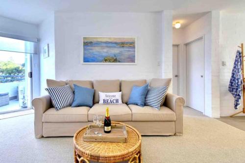 a living room with a couch and a table with a bottle of wine at Beautiful, modern apartment seconds from beach in Perth
