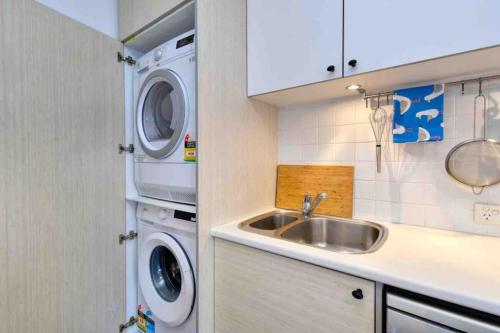 a kitchen with a sink and a washing machine at Beautiful, modern apartment seconds from beach in Perth