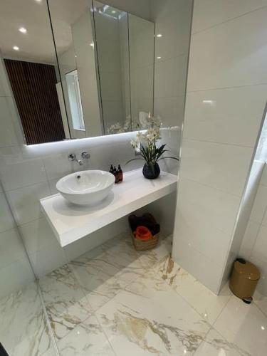 a white bathroom with a sink and a mirror at Home in Wirral - Peaceful Contemporary Gem. in Wirral