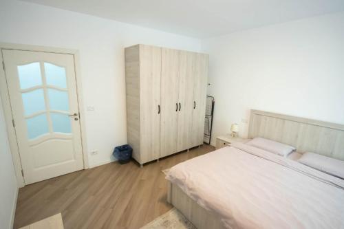 a white bedroom with a bed and a cabinet at DownTown Apartments in Rădăuţi