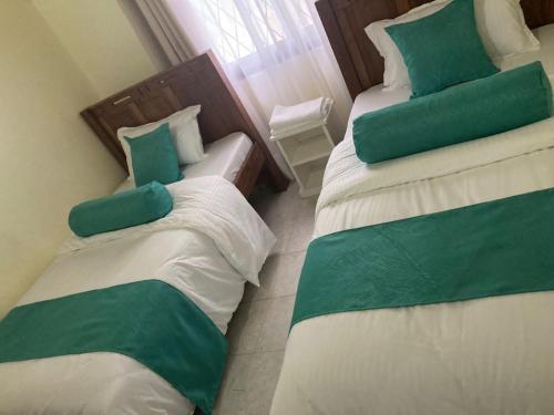 - 2 lits dans une chambre de couleur verte et blanche dans l'établissement Mtwapa Villa, à Mombasa