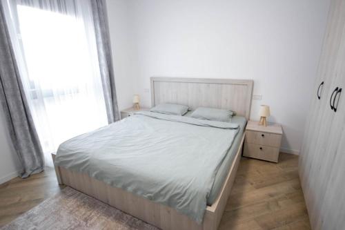 a white bedroom with a bed and a window at DownTown Apartments in Rădăuţi
