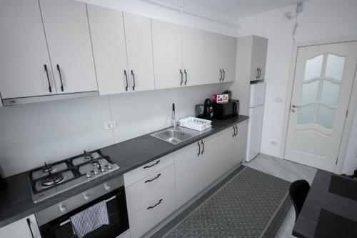 a kitchen with white cabinets and a sink and a stove at DownTown Apartments in Rădăuţi