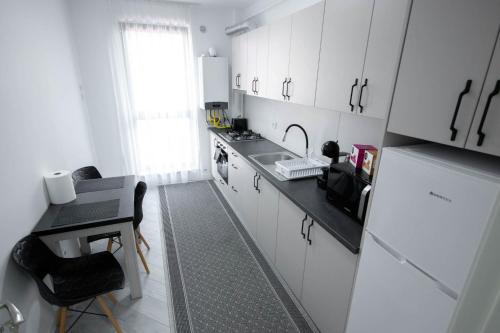 a kitchen with white cabinets and a black counter top at DownTown Apartments in Rădăuţi