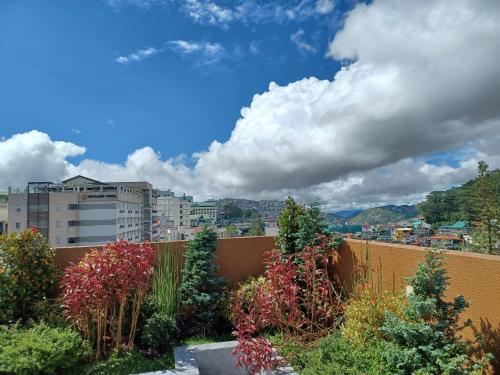 een steunmuur met bloemen en bomen in een stad bij Gabs CozyHomes at MegaTower IV Condo, City Center Baguio in Baguio