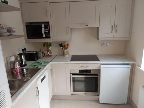 a kitchen with white cabinets and a stove top oven at Harmony Haven Cottage in Foxford