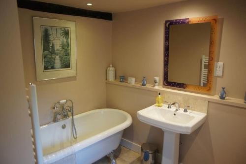 La salle de bains est pourvue d'un lavabo, d'une baignoire et d'un miroir. dans l'établissement IVY COTTAGE, à Pulborough